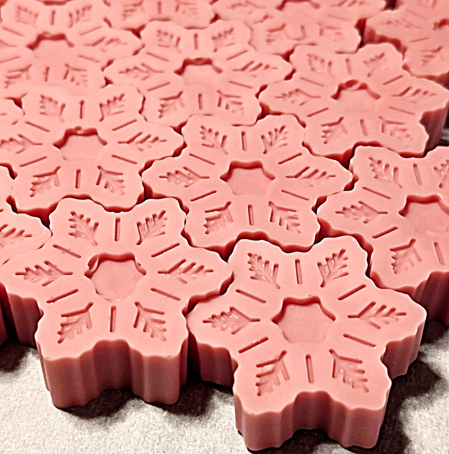 Pink wax melts with snowflake patterns on a gray surface
