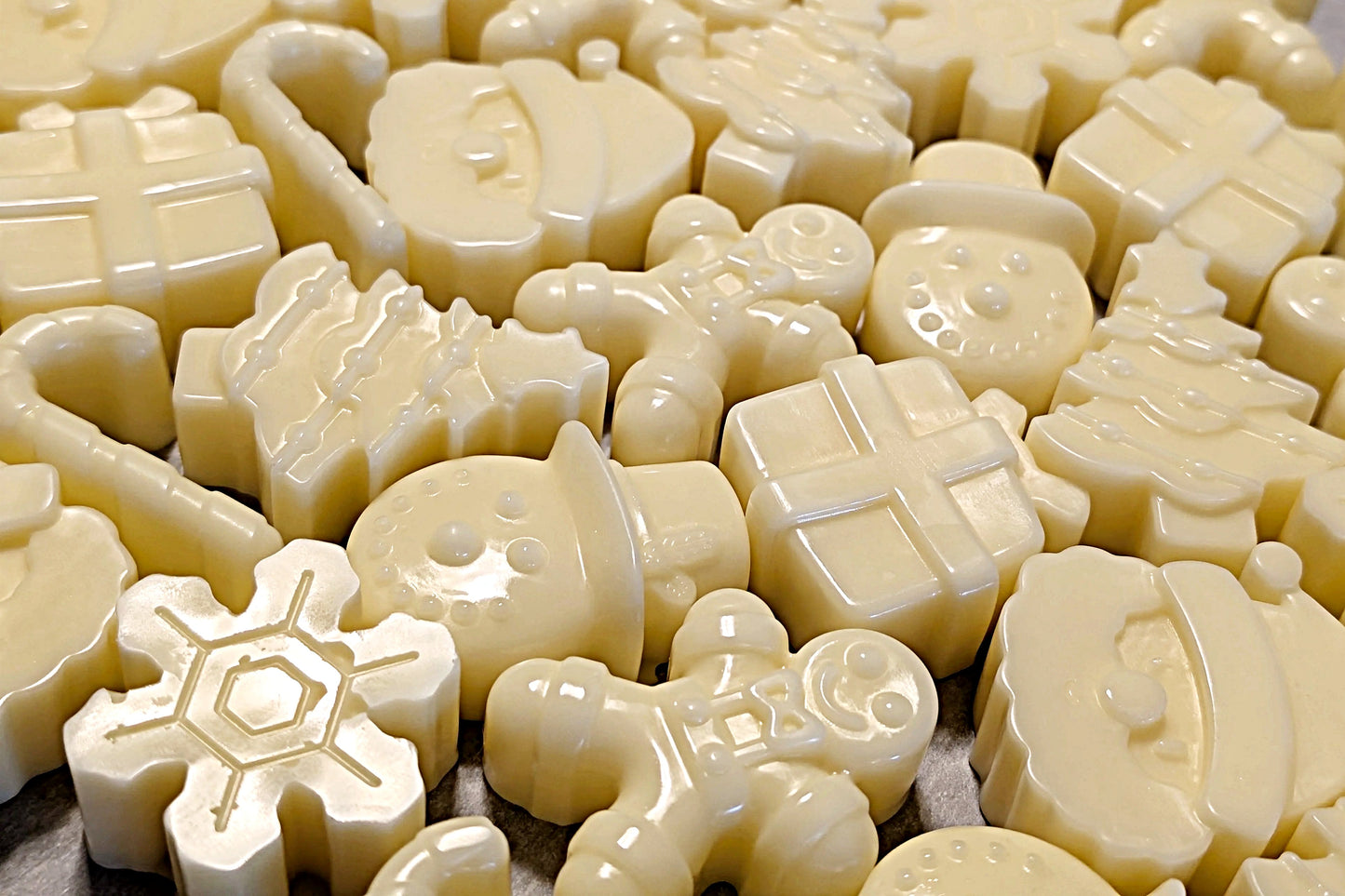 Collection of white wax melts shaped like various holiday objects on a flat surface.
