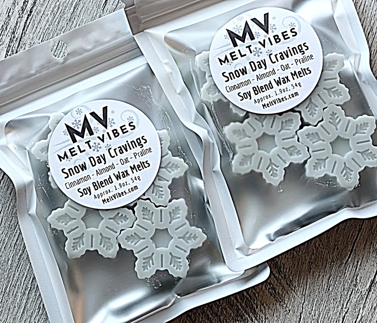 Silver bags of snowflake-shaped wax melts labeled "Melt Vibes Snow Day Cravings."