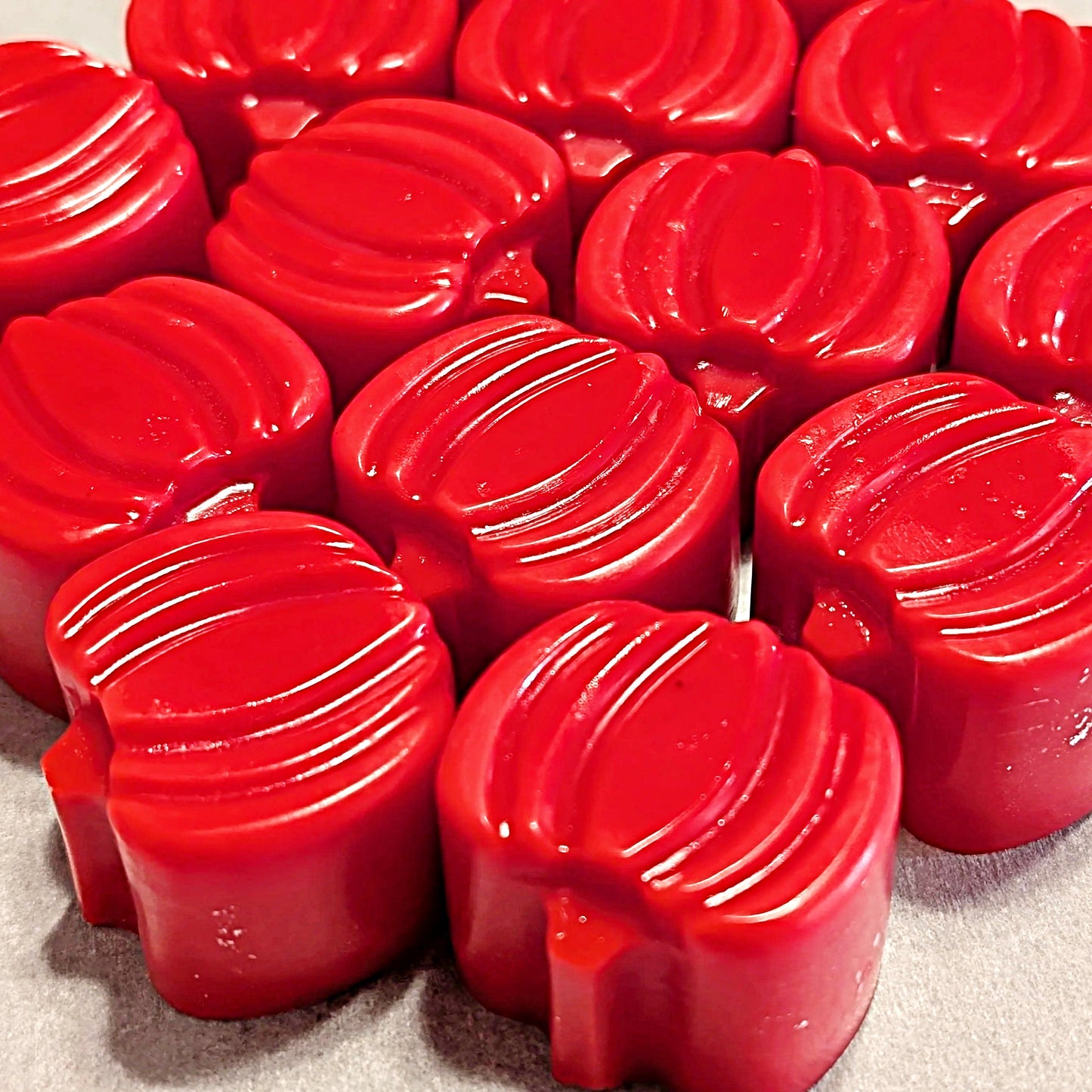 Red pumpkin shaped wax melts on a gray surface