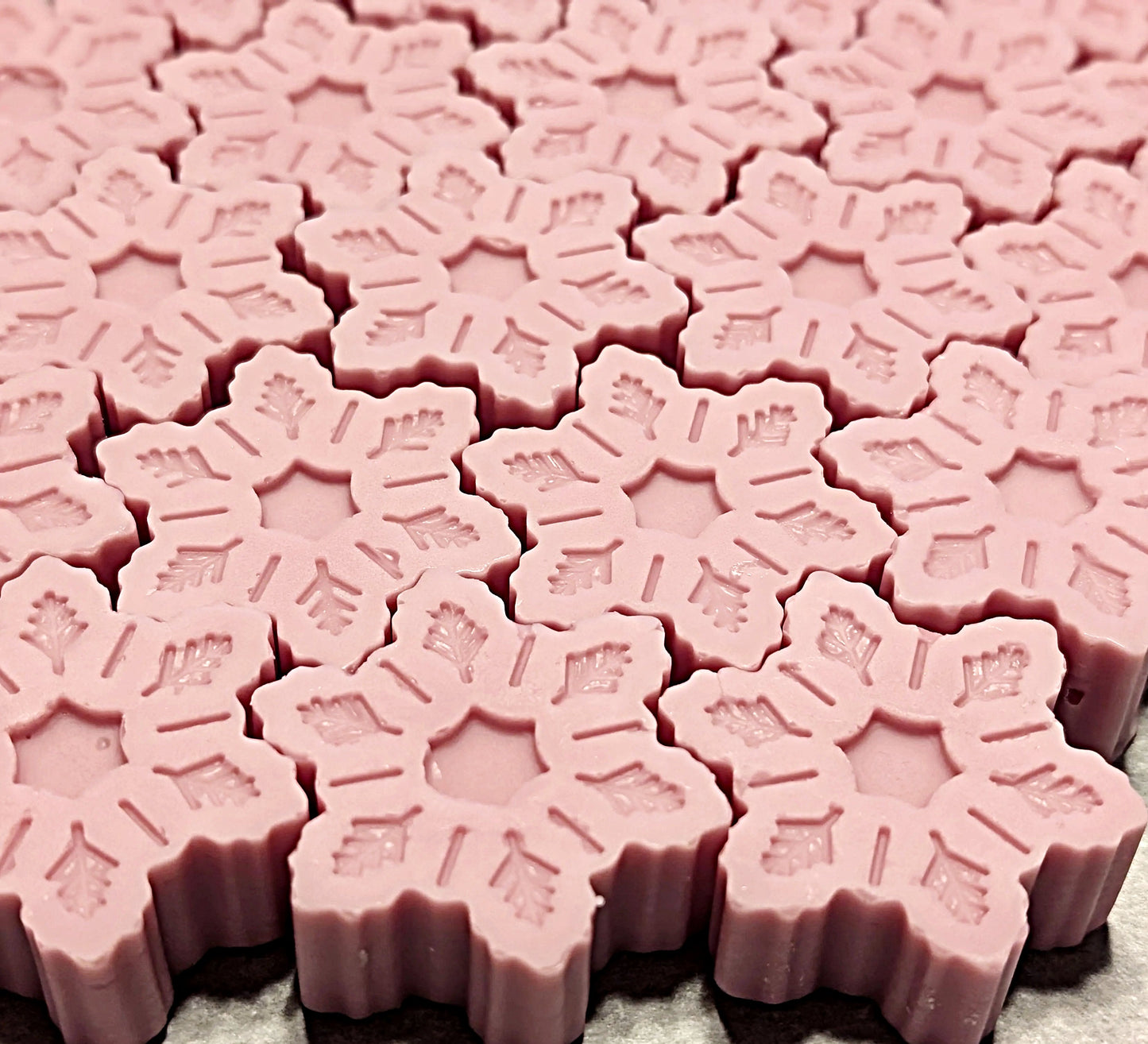 Close-up of pink snowflake-shaped wax melts on a light gray background
