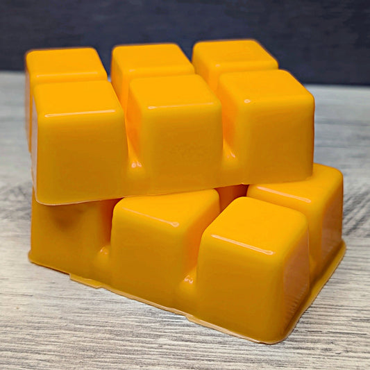Stack of yellow wax melt cubes on a wooden surface with a dark background