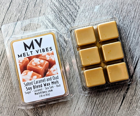 Two clear plastic clamshell packages of MELT VIBES wax melts on a gray wood surface. The left package shows the front label reading 'Salted Caramel and Oud' with a photo of caramel pieces and white salt crystals.